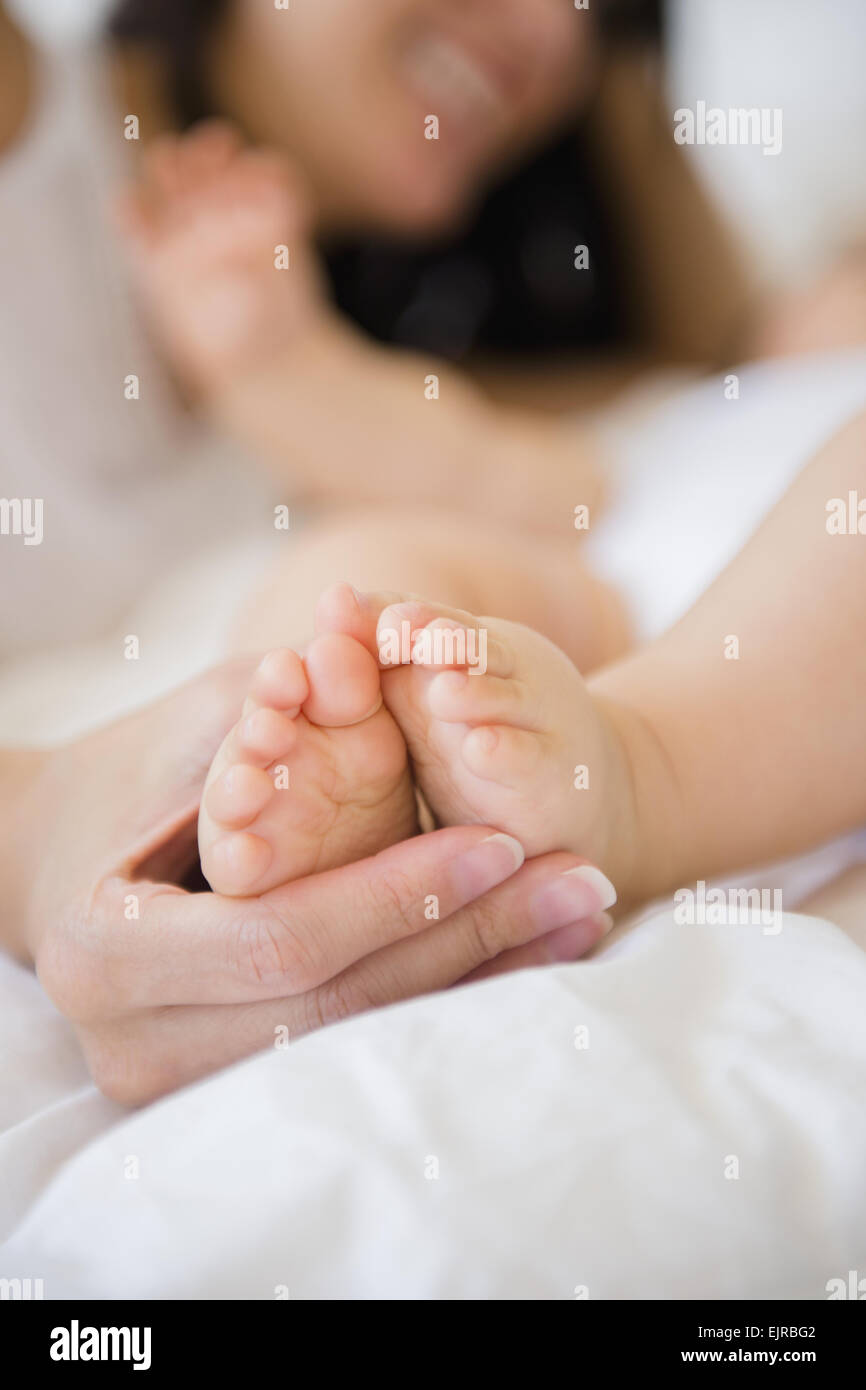 Nahaufnahme von Mischlinge Mutter hält Füße des Babys Stockfoto