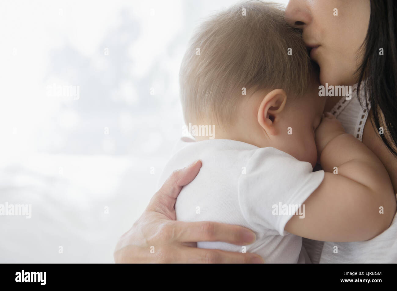 Nahaufnahme von Mischlinge Mutter Baby auf Stirn küssen Stockfoto