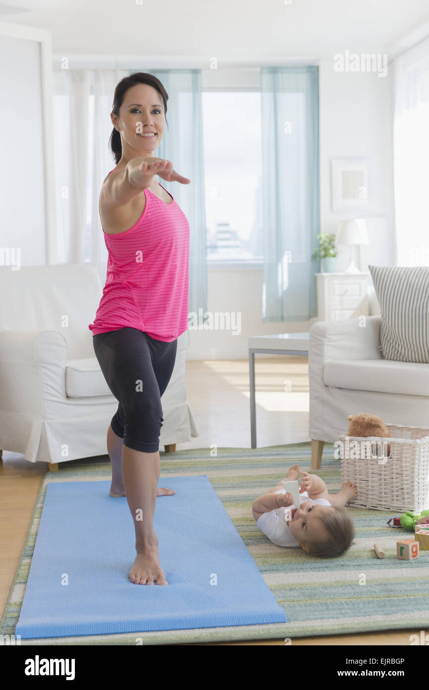 Mischlinge Mutter Yoga zu praktizieren und Baby zu Hause beobachten Stockfoto