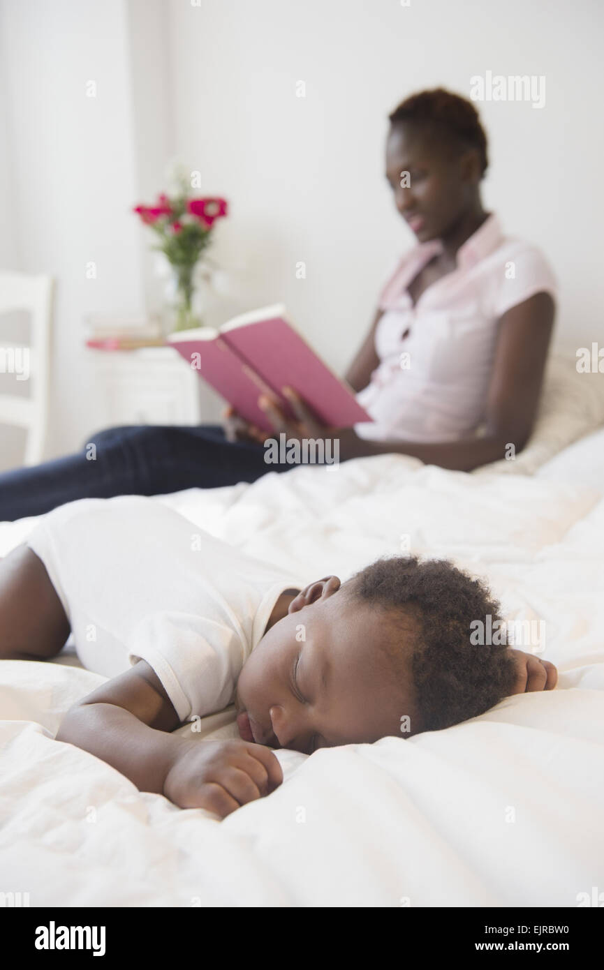 Schwarze Mutter lesen in der Nähe schlafen Baby boy Stockfoto