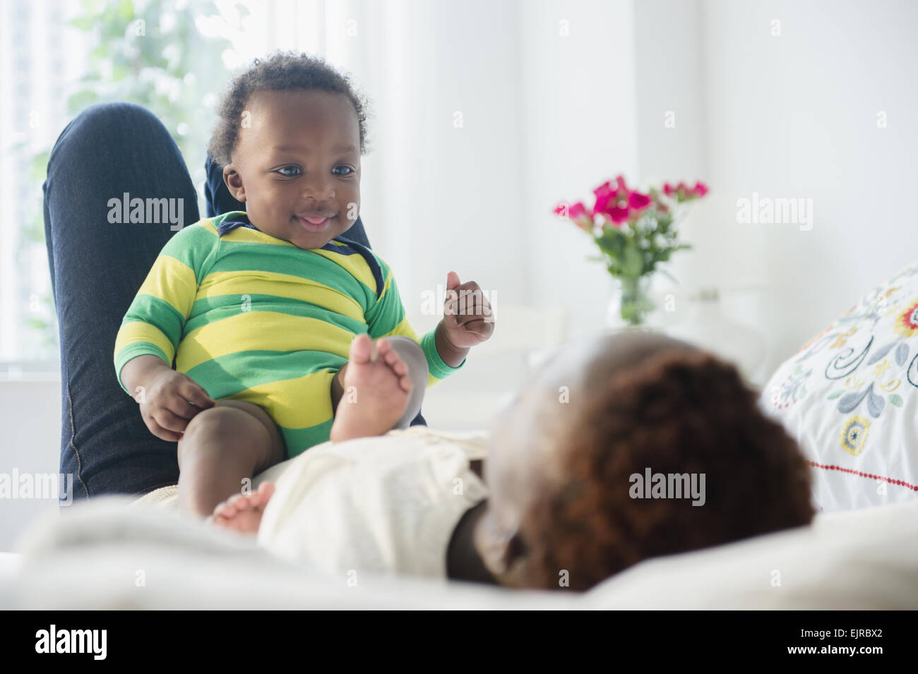 Schwarze Mutter mit Baby im Bett spielen Stockfoto