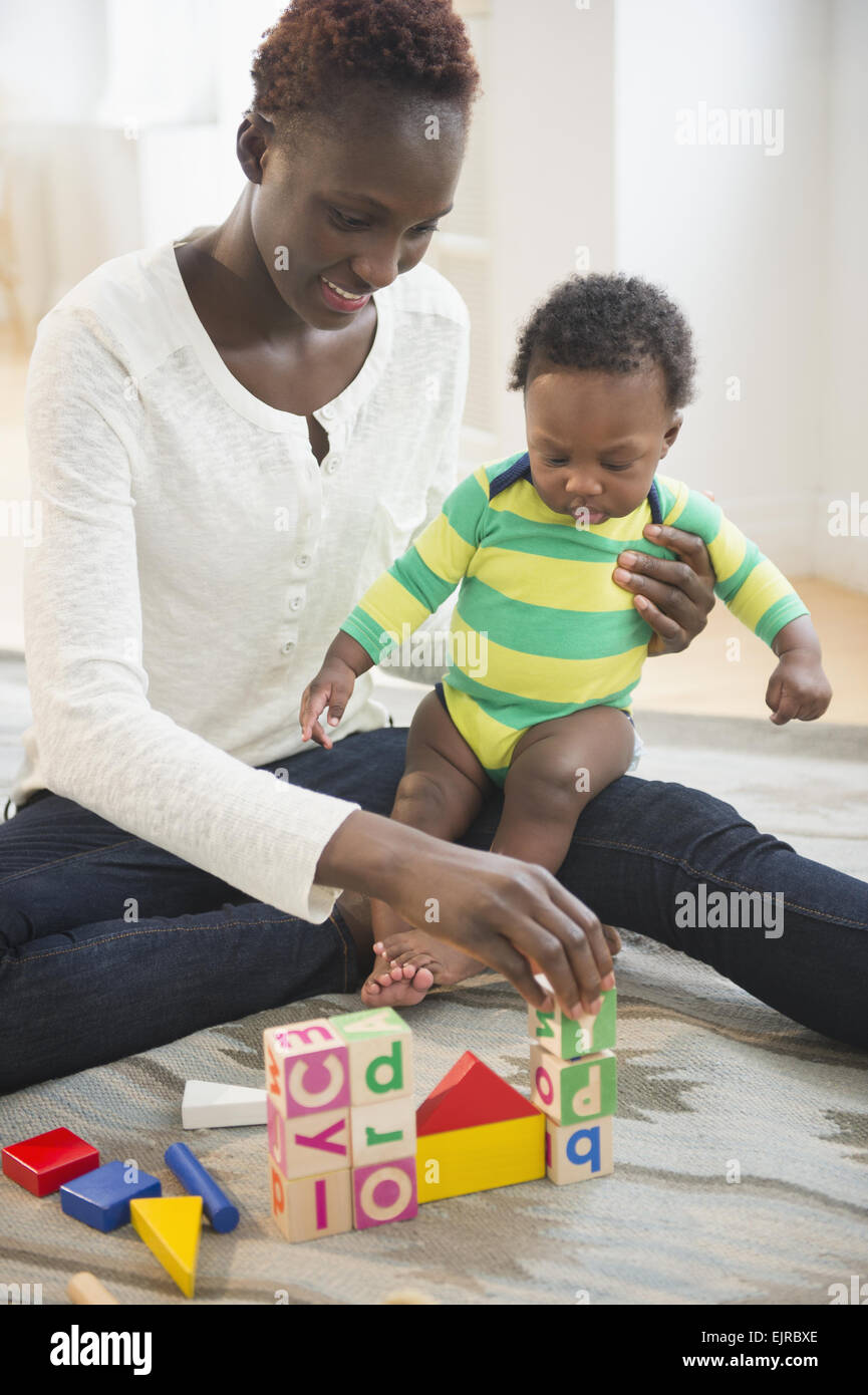 Schwarze Mutter mit Baby im Wohnzimmer spielen Stockfoto