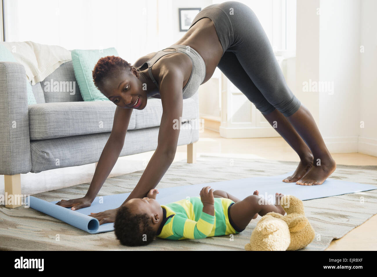 Schwarze Mutter praktizieren Yoga mit Baby im Wohnzimmer Stockfoto