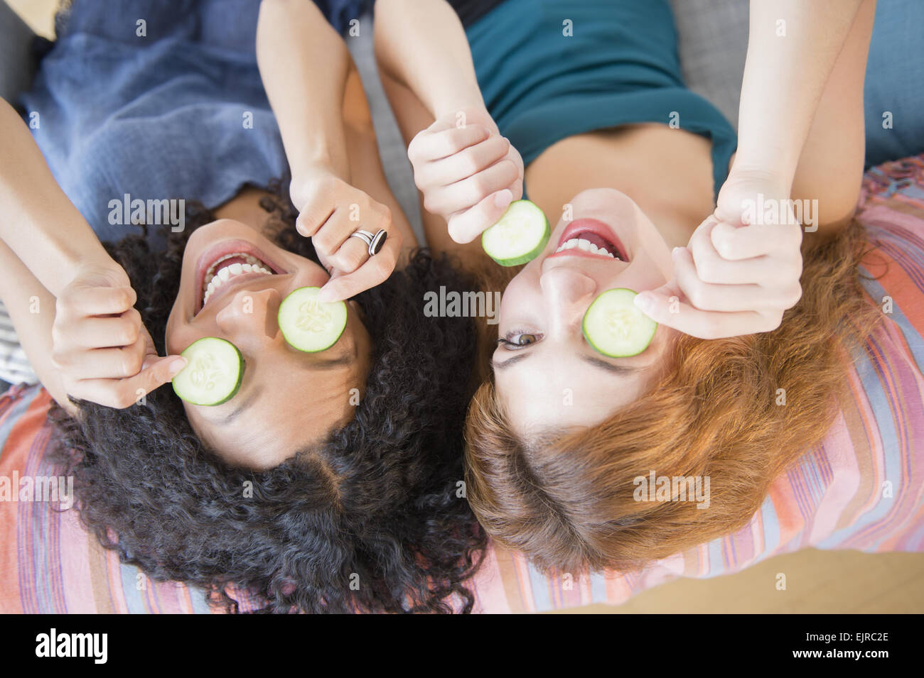 Frauen mit Gurkenscheiben über Augen Stockfoto