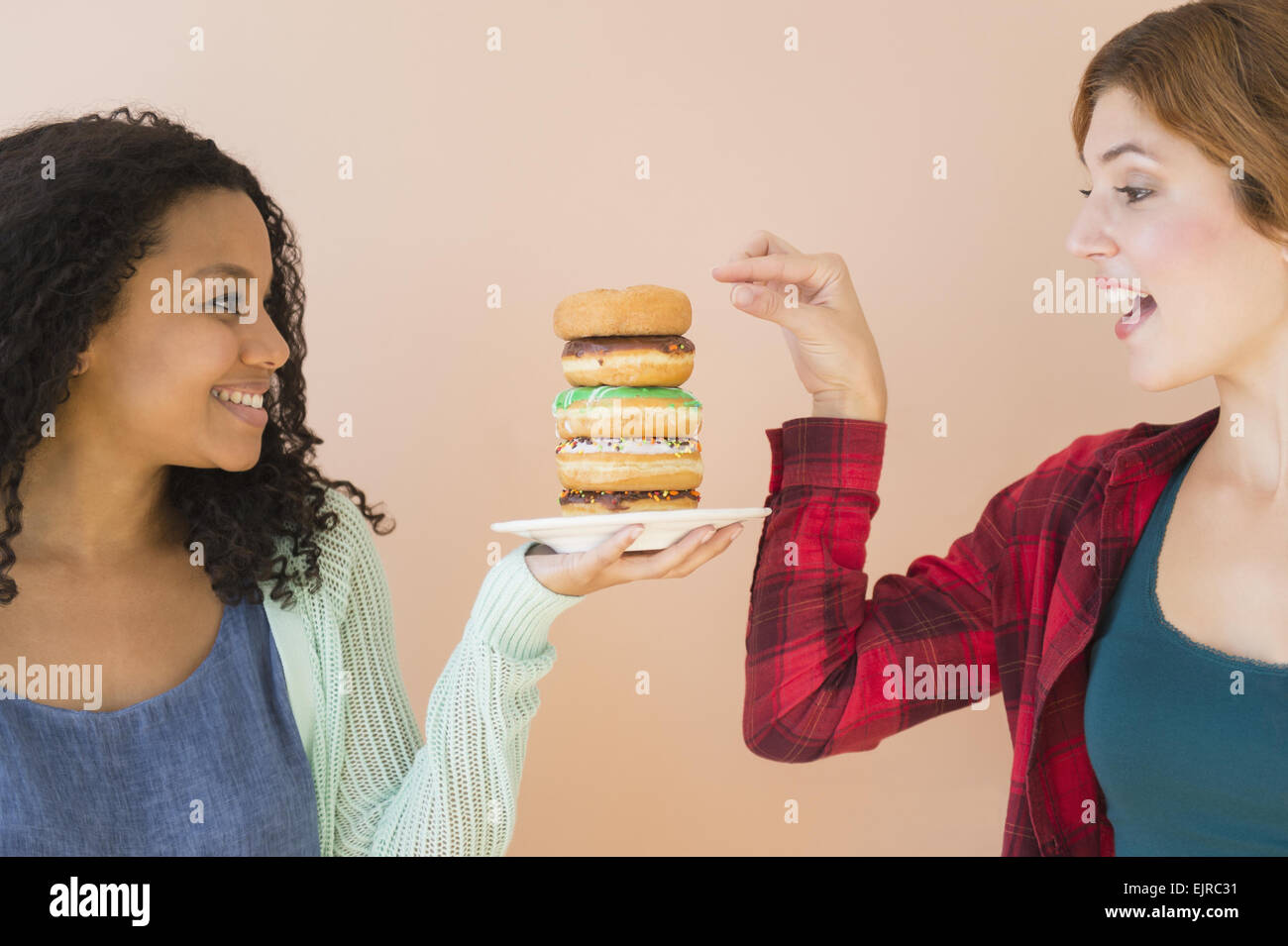 Frauen genießen Stapel Donuts Stockfoto