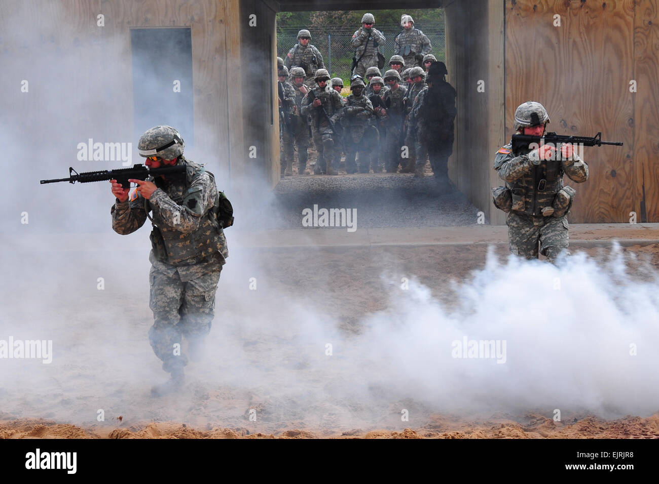 U.S. Armee Personal Sgts. Patrick Sumey und Terry Cooper, beide Lehrer für die einsatzvorbereitende Ausbildung Hilfe Element Initiative sprint durch den Nebel aus einem Rauch Kanister als Studenten und Dozenten Ansicht vom Startpunkt auf Lager Äsche, Michigan Die Soldaten sind Schulungen für die Bereitstellung durch die Teilnahme an der National Guard Stockfoto