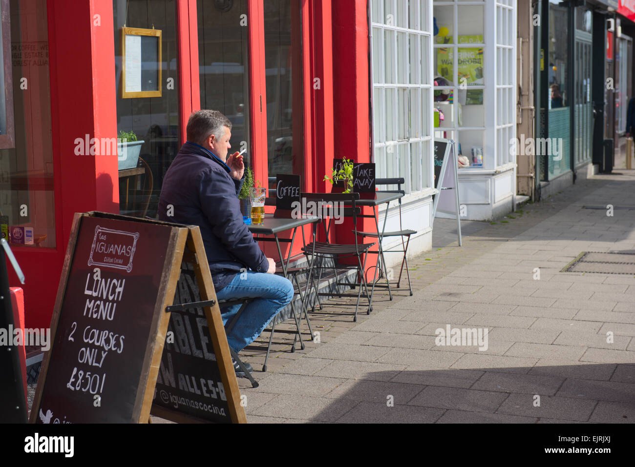 Mann sitzt Bar im Freien in der Sonne mit Pint Bier und Zigarette Stockfoto