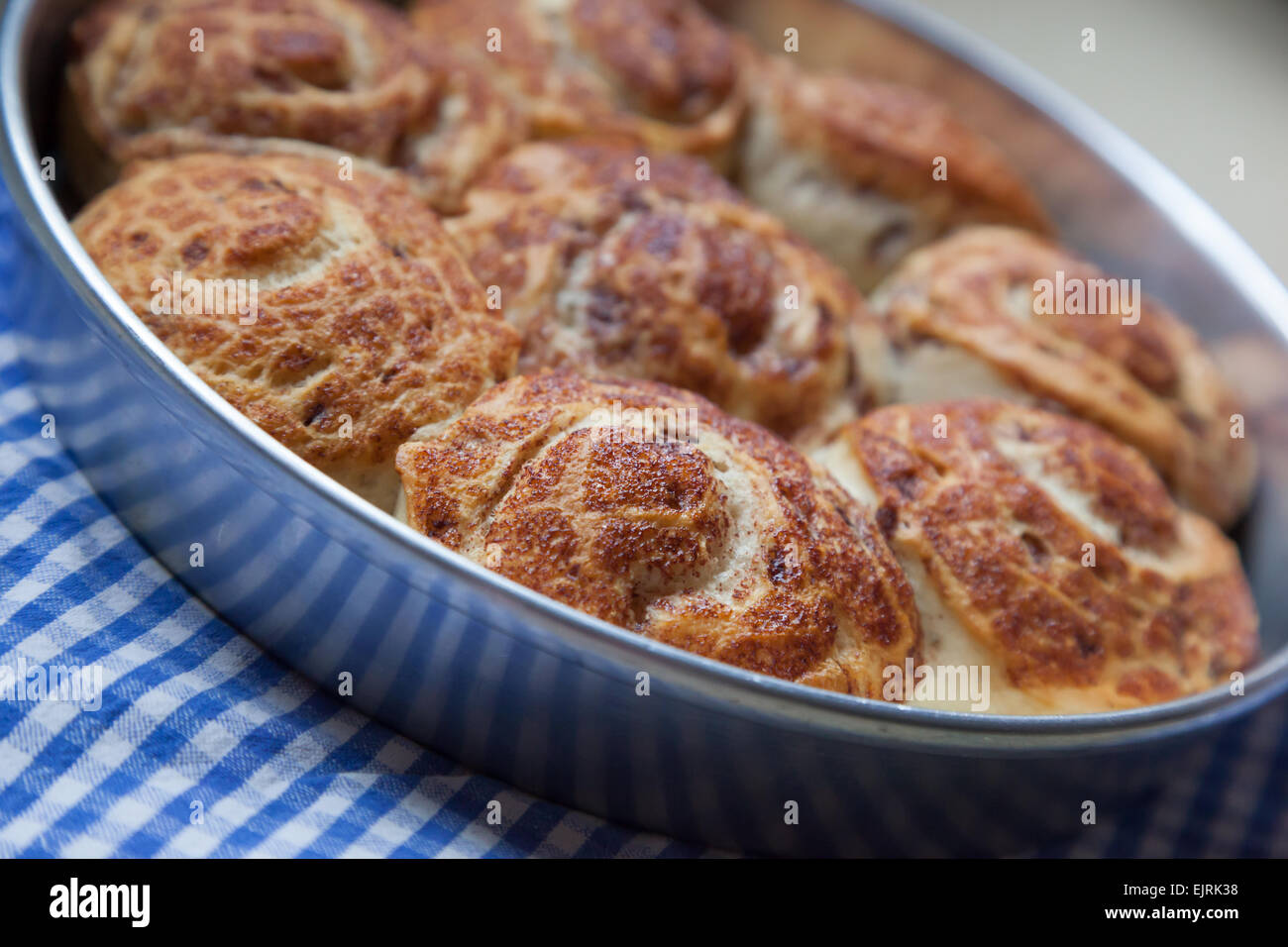 Zimtschnecken sitzen auf einem blau-weißen aufgegebenes Tuch, frisch aus dem Ofen. Stockfoto