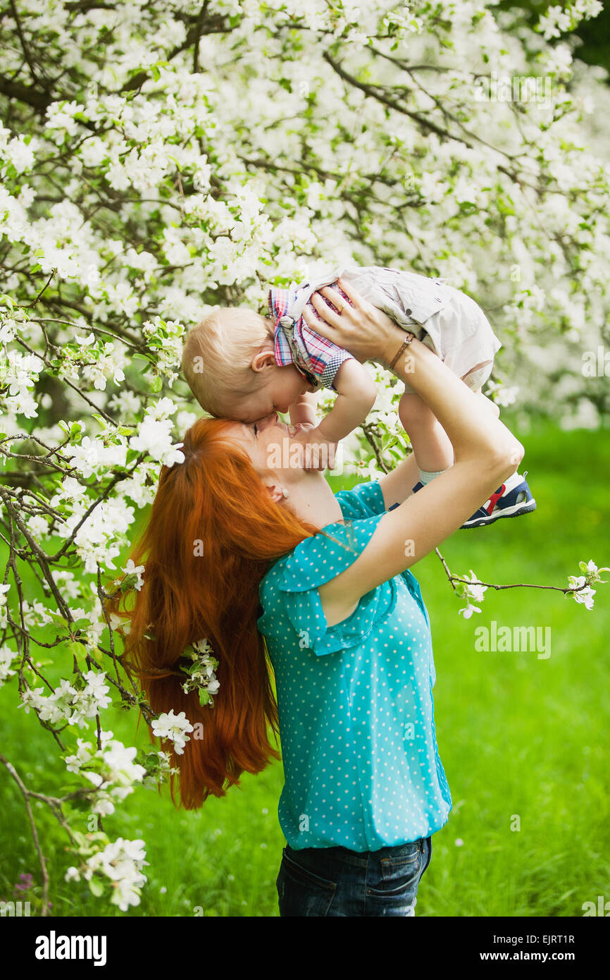 Porträt von glücklich glückliche Mutter und Sohn im Frühlingsgarten. Sie spielen und lachen. Blühende Apfelbäume. Familien-Konzept. Stockfoto