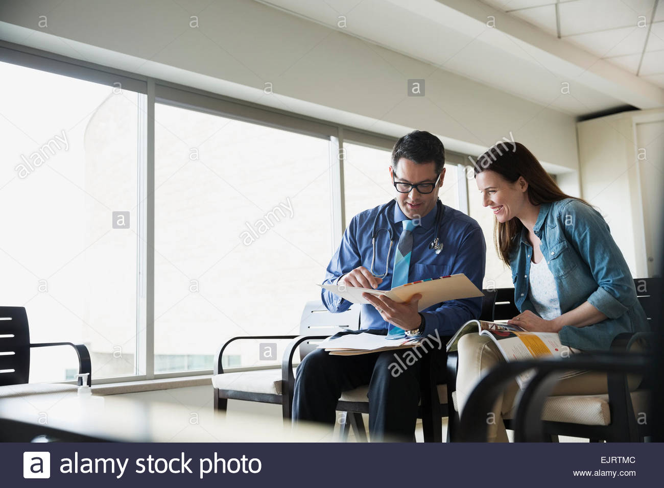 Arzt, die Überprüfung der medizinischen Diagramm mit Patienten Wartezimmer Stockfoto