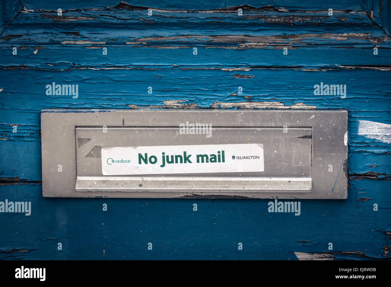 Ein Briefkasten auf eine verwitterte Tür im Norden Londons mit einem "No Junk-Mail"-Aufkleber. Stockfoto