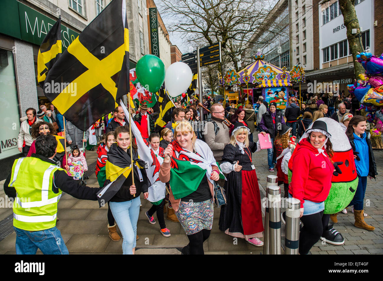 Menschen winken Waliser nationale Flaggen und Banner marschieren durch die Straßen nehmen Teil in "AberDewi" - Schutzpatron St. Davids Tag feiern in Swansea Wales Großbritannien, Stockfoto