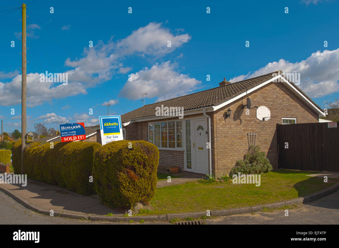 Ein Bungalow mit 2 konkurrierenden Immobilienmakler Bretter außerhalb verkauft ein Sprichwort auf dem Brett im Vereinigten Königreich Stockfoto