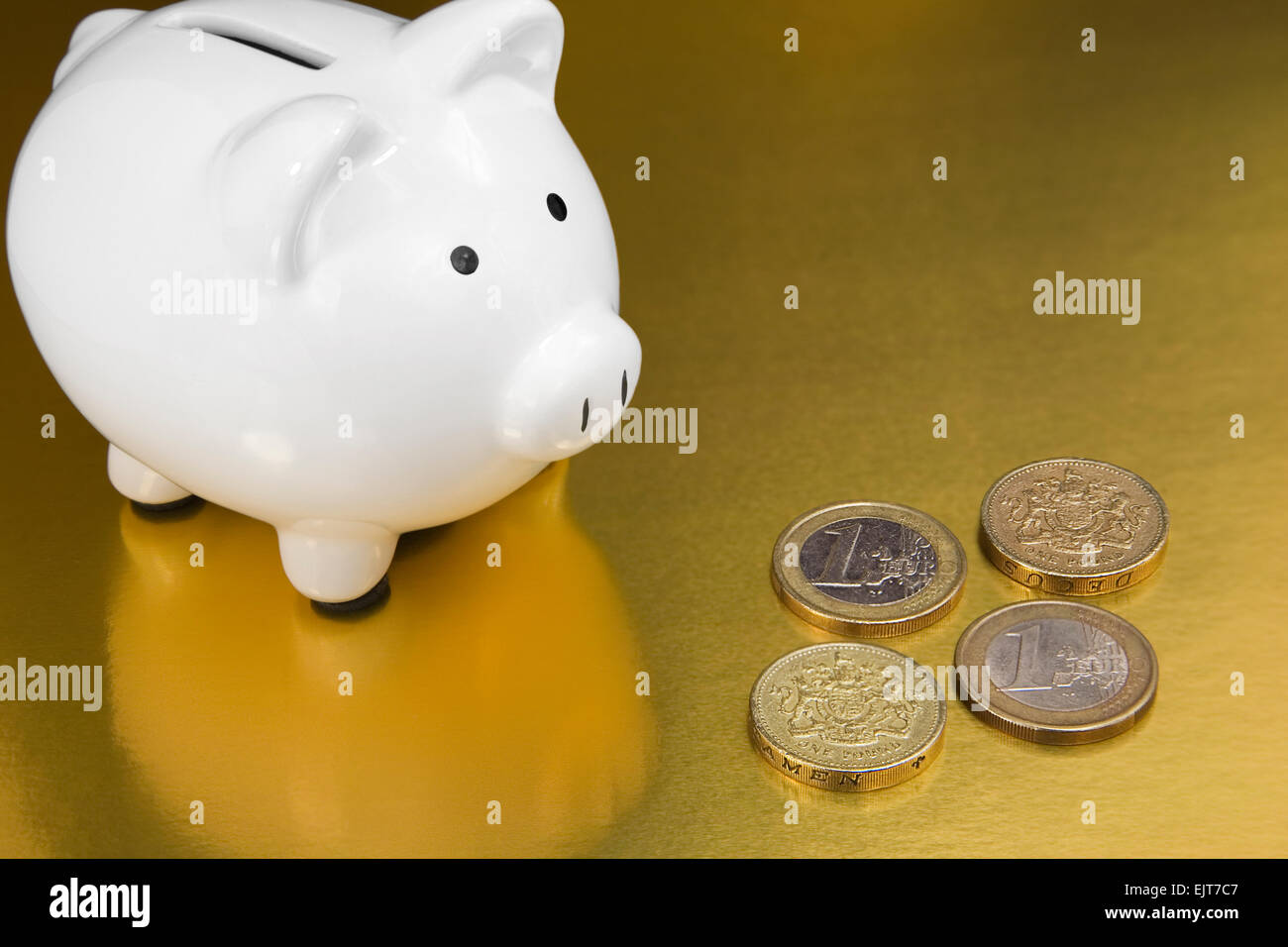 White-Sparschwein mit einem Euro-Münzen auf Goldgrund Stockfoto