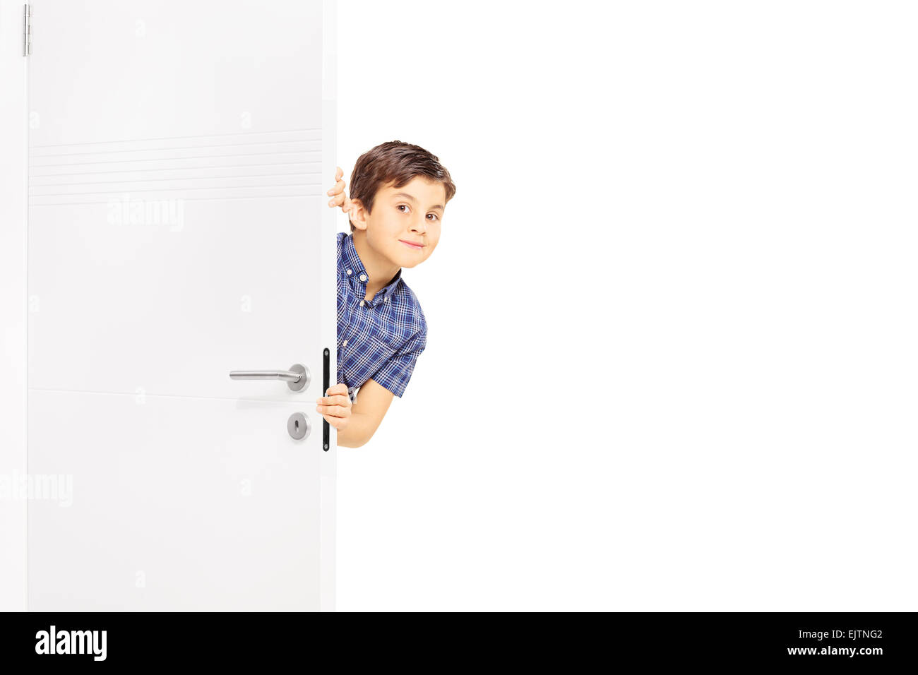 Schöner kleiner Junge heimlich einen Blick hinter einer Tür und schaut in die Kamera, die isoliert auf weißem Hintergrund Stockfoto