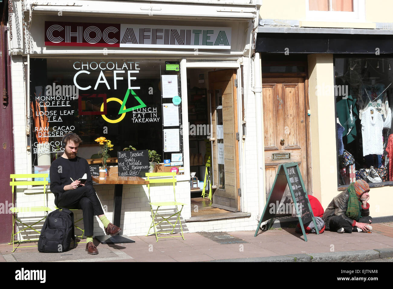 Soziale Kluft in Brighton East Sussex trendige Coffee-Shop-Benutzer und Obdachlosen Mann hart Stockfoto
