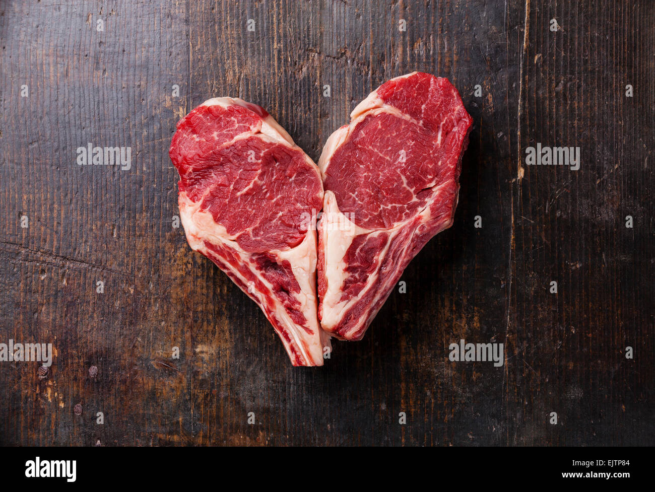 Herz Form rohes Fleisch Ribeye Steak Entrecote auf hölzernen Hintergrund Stockfoto