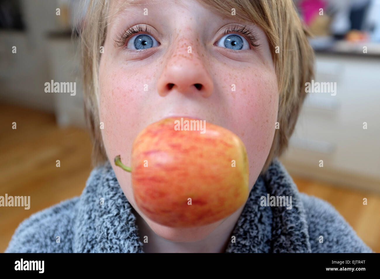 Ein Junge mit blauen Augen, die einen Apfel essen Stockfoto