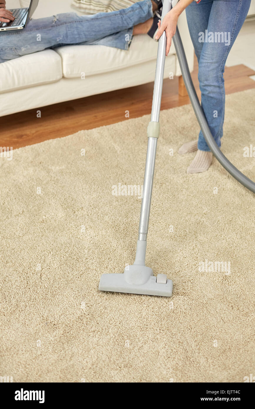 Nahaufnahme von Paar Beine und Staubsauger zu Hause Stockfoto