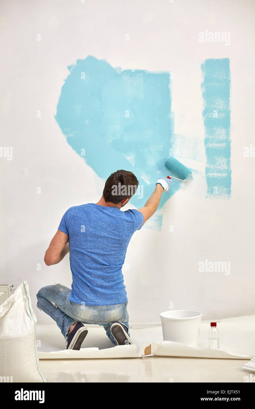 Mann mit Walze Malerei Wand in blau zu Hause Stockfoto