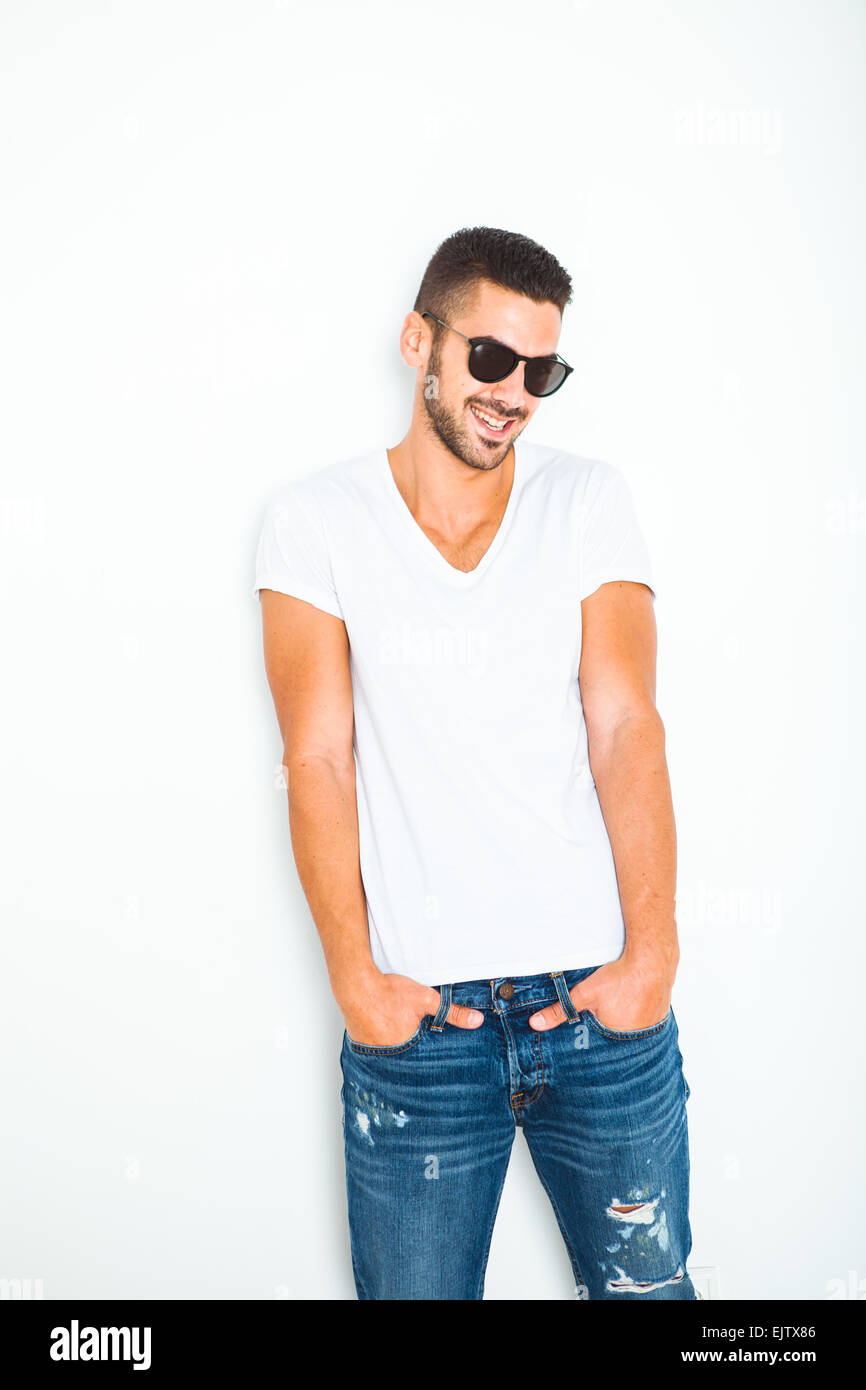 lässige schönen jungen Mann im weißen Hemd neben einer Wand mit Sonnenbrille Stockfoto