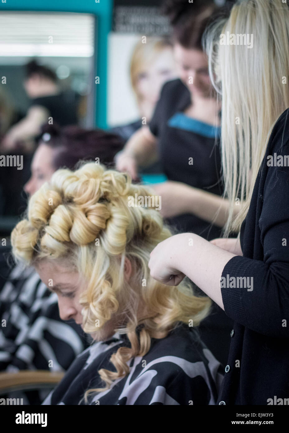Friseur styling zwei weibliche Modelle in einem Friseursalon für eine Modenschau mit jener in den Vordergrund mit lockigen blonden Haaren Stockfoto