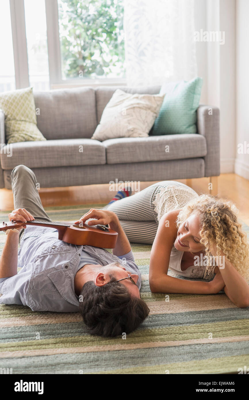 Paar liegend am Boden spielt ukulele Stockfoto