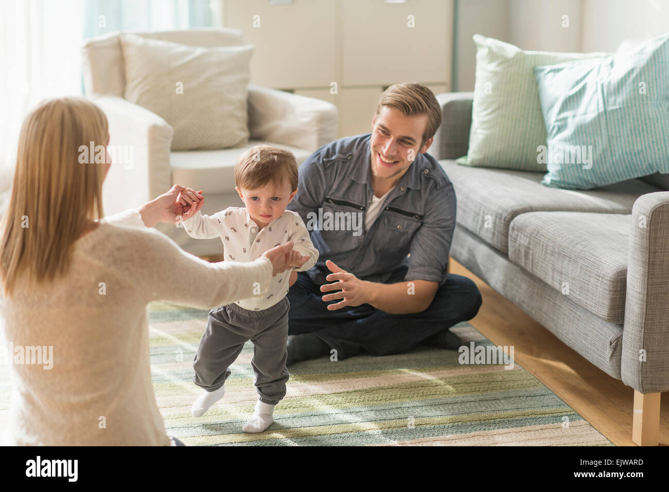 Glückliche Eltern helfen Söhnlein (2-3 Jahre) zu Fuß im Wohnzimmer Stockfoto