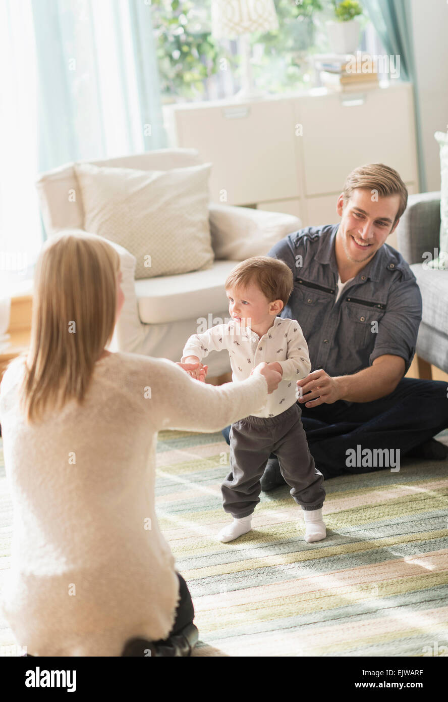 Glückliche Eltern helfen Söhnlein (2-3 Jahre) zu Fuß im Wohnzimmer Stockfoto