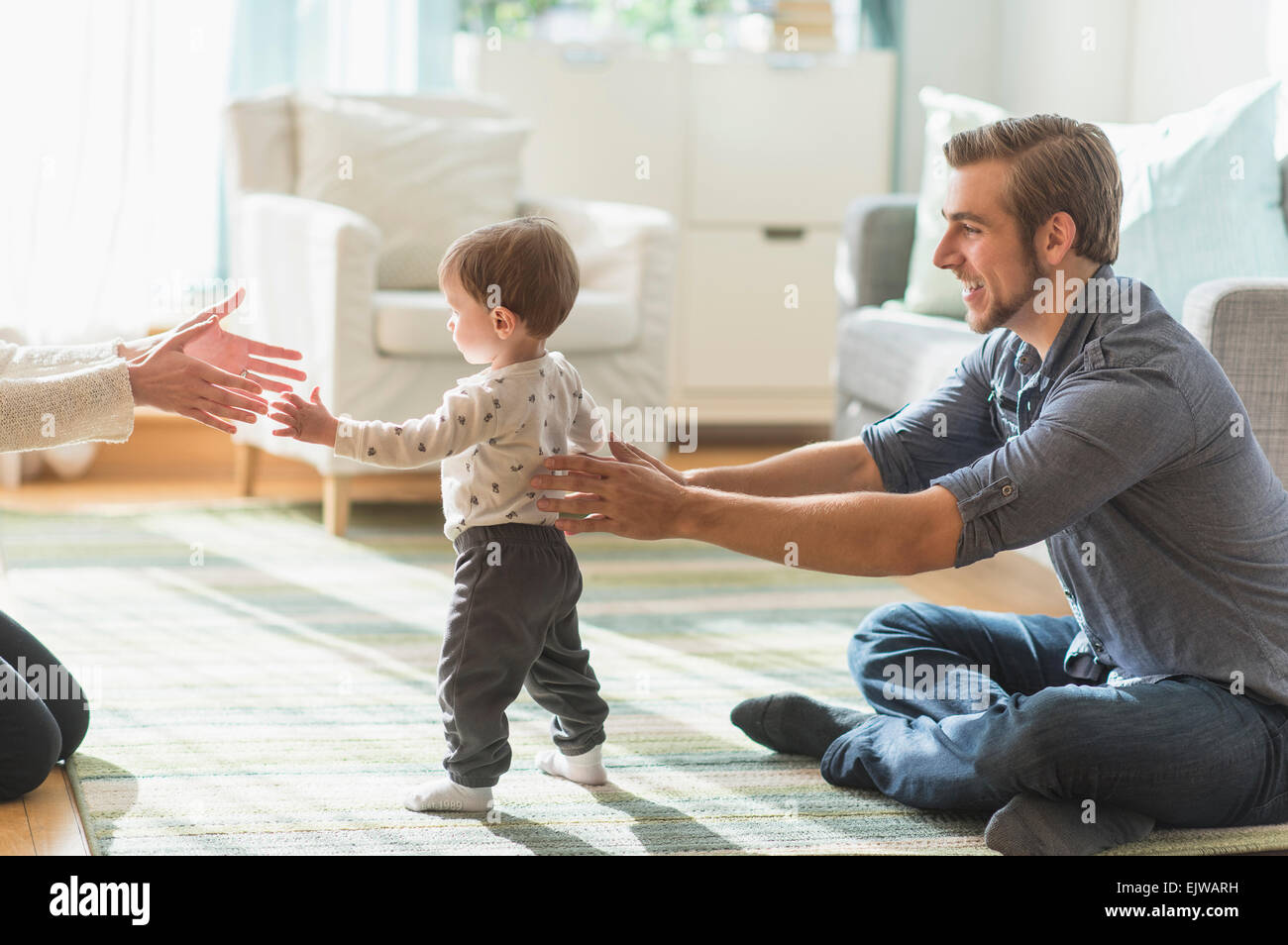 Glückliche Eltern helfen Söhnlein (2-3 Jahre) zu Fuß im Wohnzimmer Stockfoto