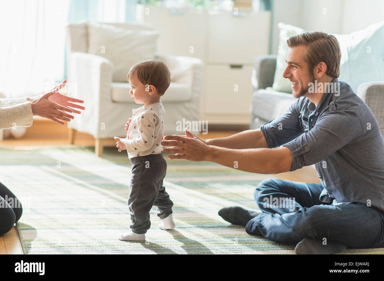 Glückliche Eltern helfen Söhnlein (2-3 Jahre) zu Fuß im Wohnzimmer Stockfoto