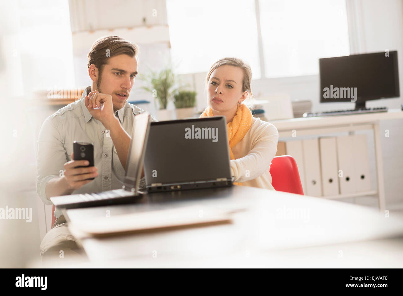 Junger Mann und Frau gemeinsam mit Laptop im Büro Stockfoto