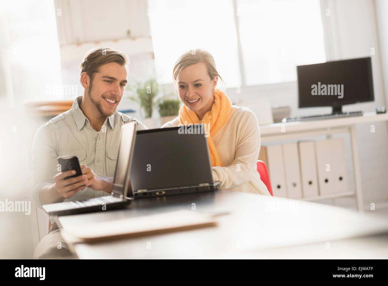 Junger Mann und Frau gemeinsam mit Laptop im Büro Stockfoto