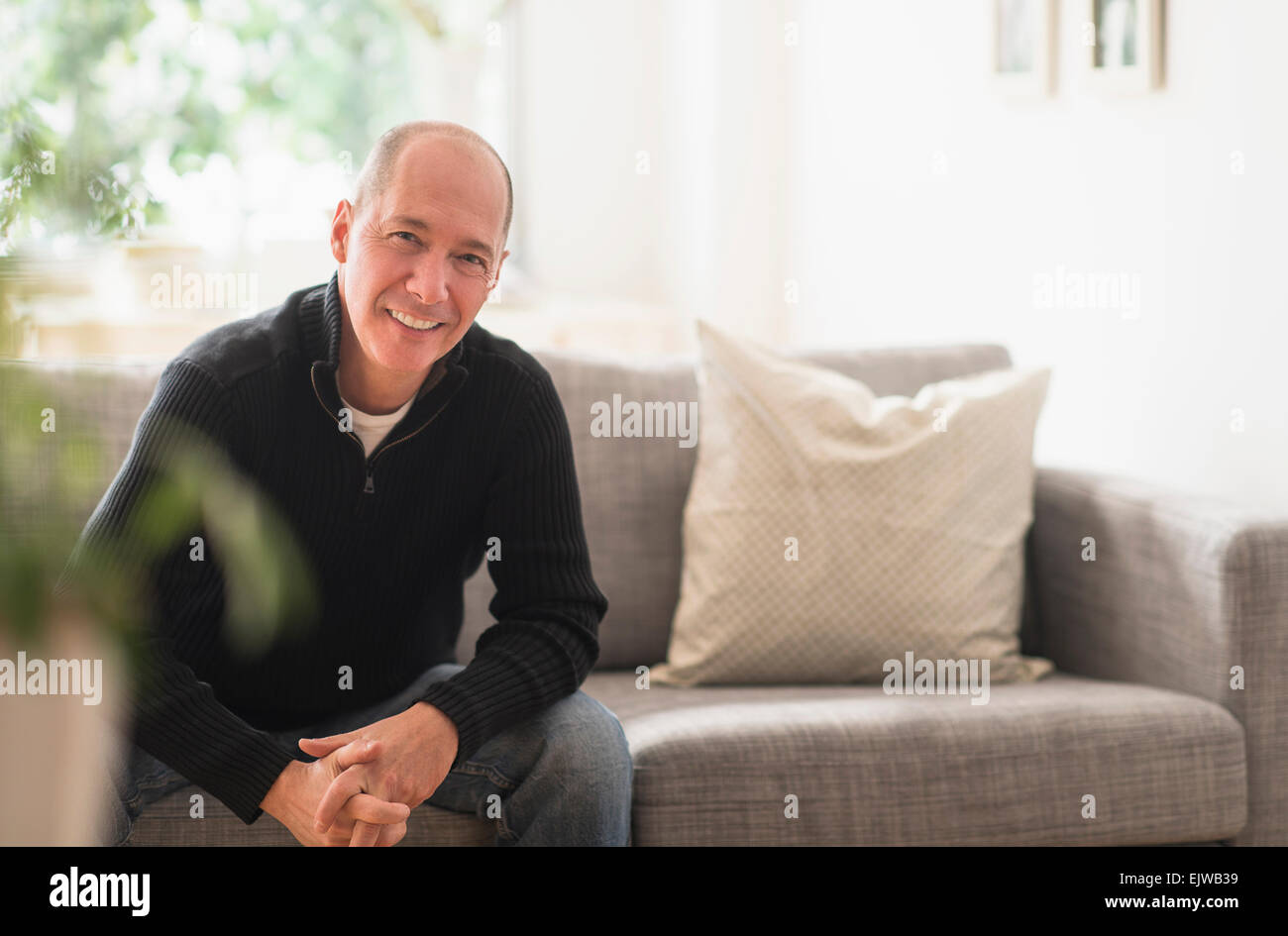 Porträt des Lächelns reifen Mannes auf Sofa im Wohnzimmer entspannen Stockfoto