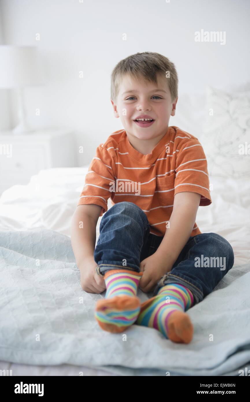 Porträt von Boy (6-7) auf Bett sitzend Stockfoto
