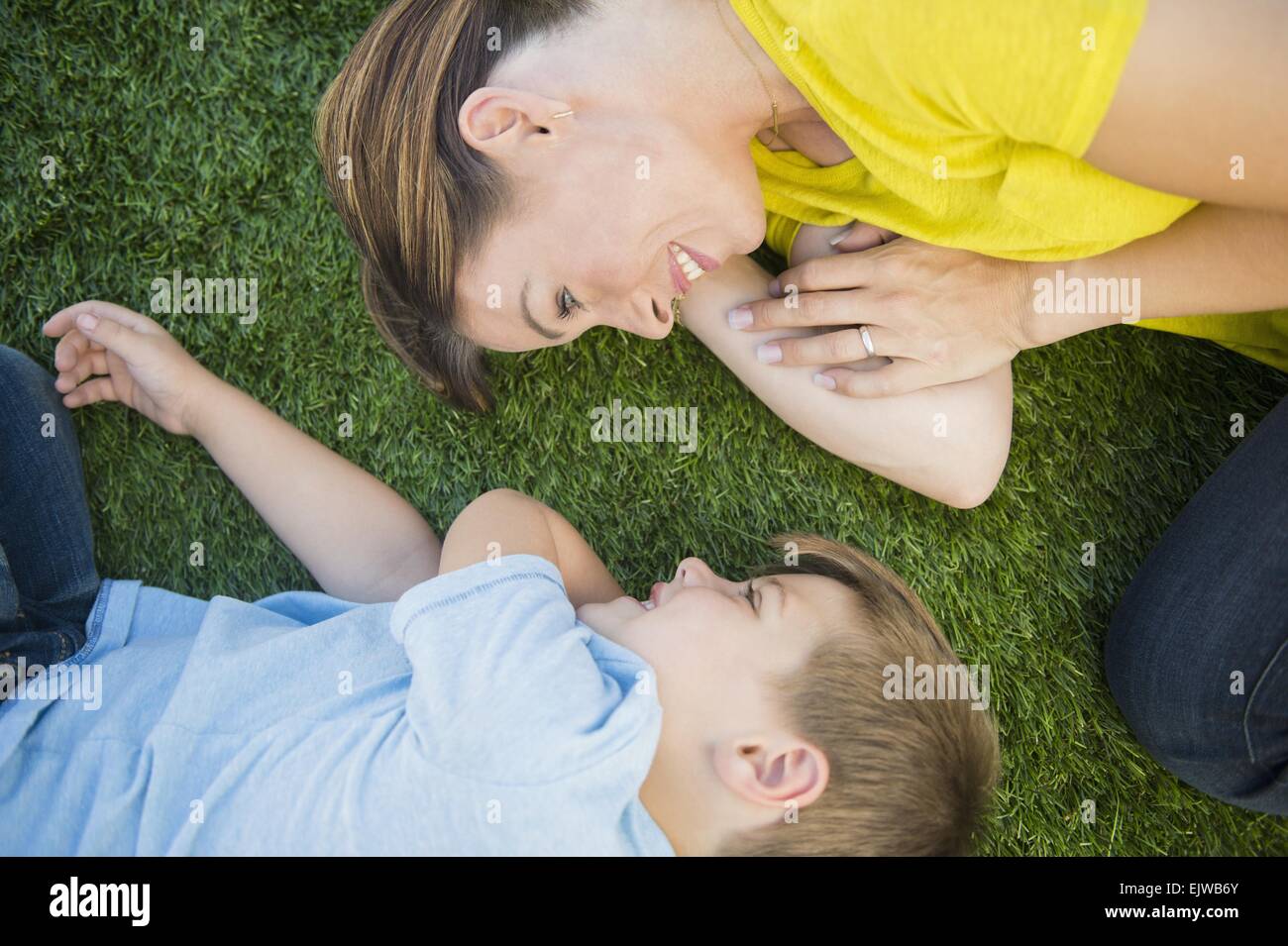 Mutter und Sohn (6-7) entspannend auf Rasen Stockfoto