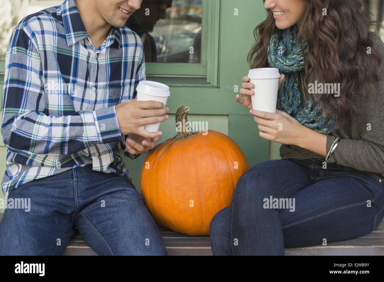 USA, Staat New York, New York City, Brooklyn, junges Paar sitzt auf der Bank mit Kaffeetassen Stockfoto