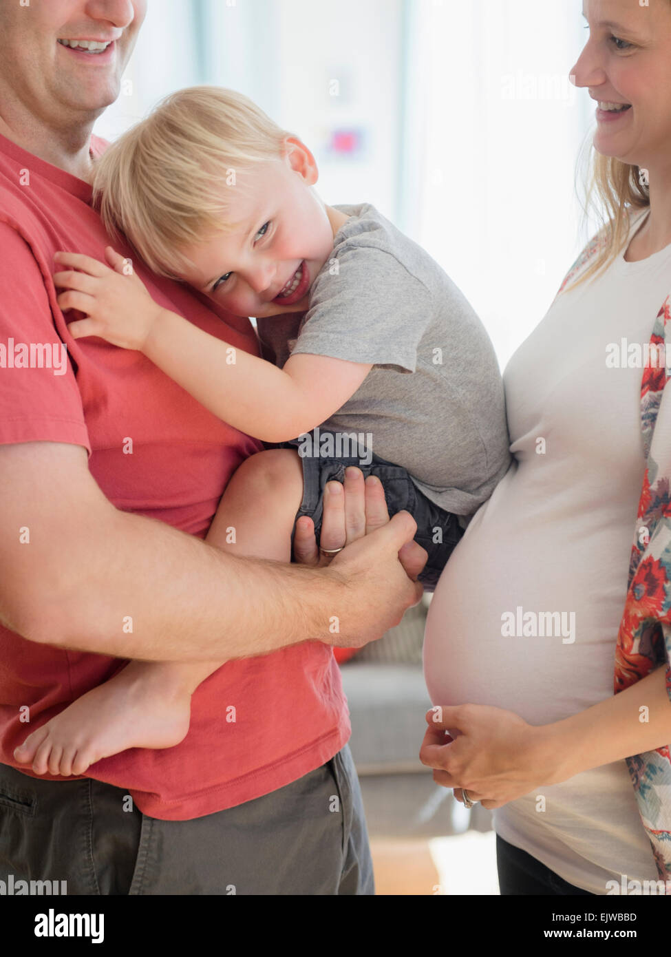 Fröhlicher Junge (2-3) verbringt Zeit mit seinen Eltern im Wohnzimmer Stockfoto