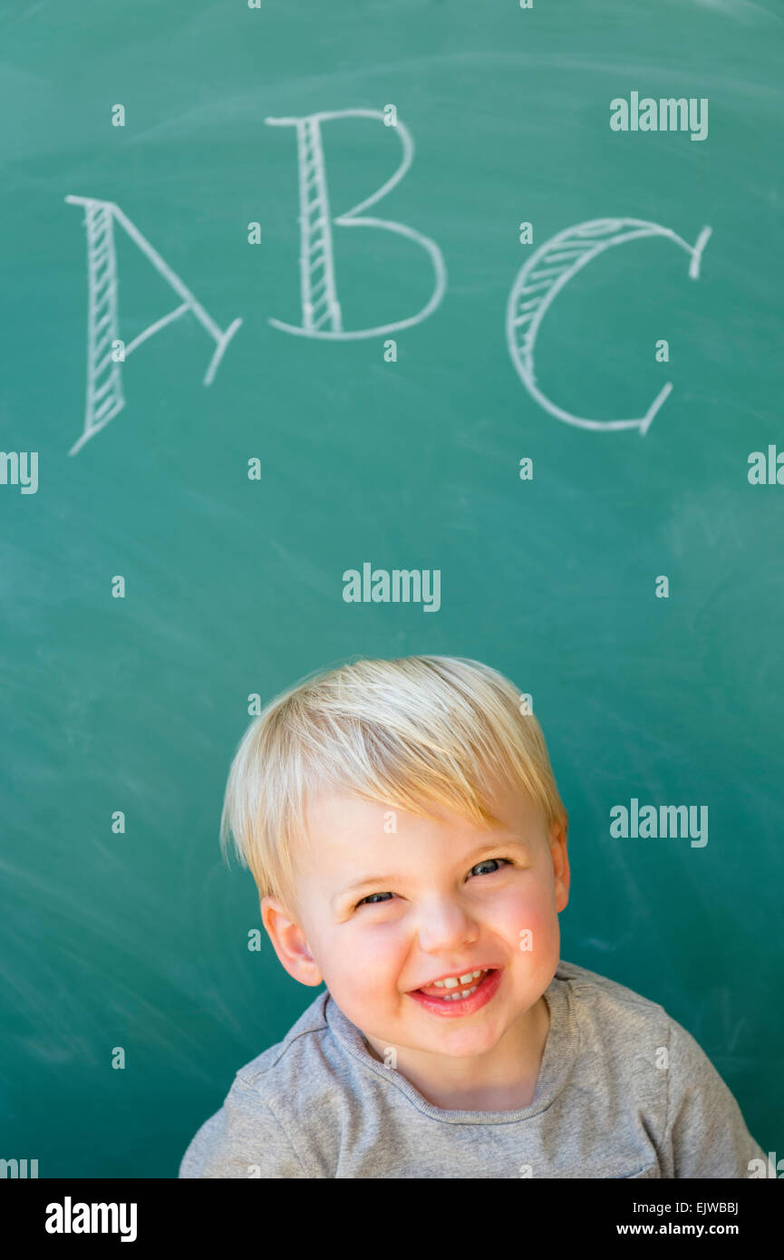 Jungen (2-3) lächelnd vor Tafel mit Buchstaben ABC geschrieben Stockfoto