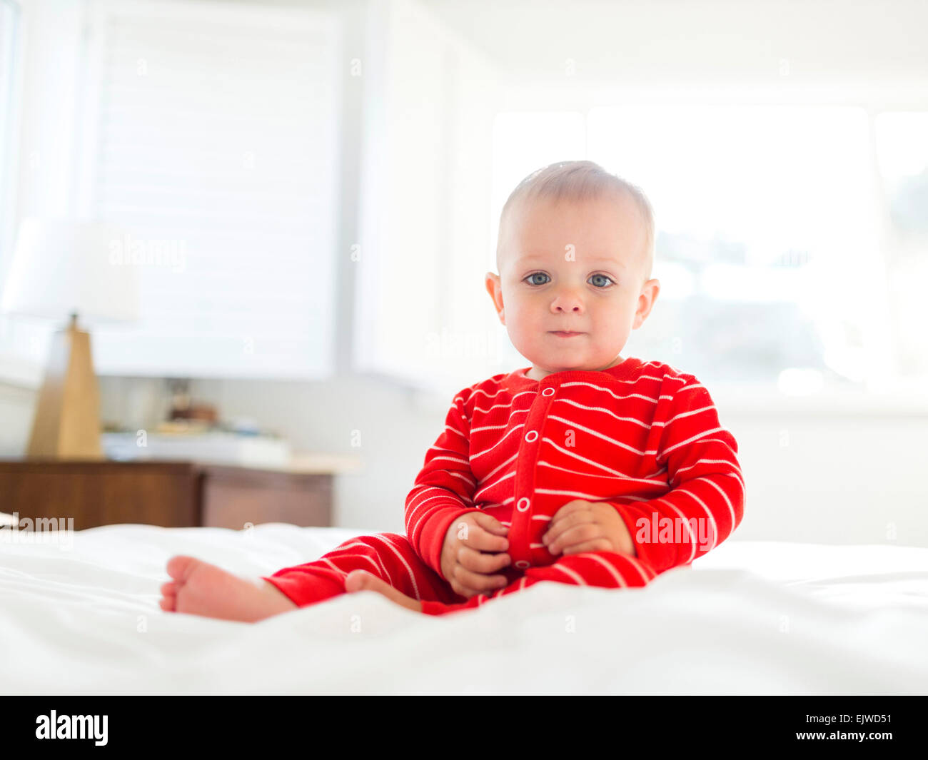 (2-3) junge im gestreiften Pyjama sitzt auf Bett Stockfoto