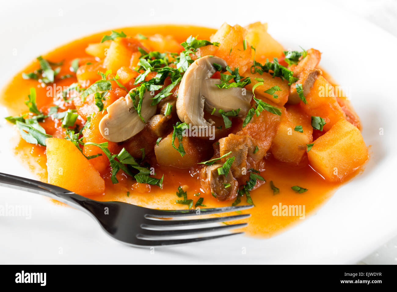 Kartoffeln mit Pilzen auf weißen Teller mit Gabel Stockfoto