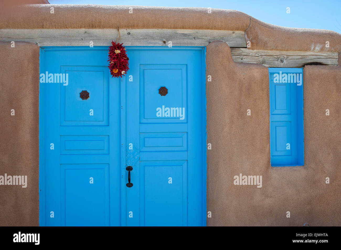 USA New Mexico NM Ranco de Taos Adobe Wand und Tür Detail mit Chile Girlanden über der Tür hängen Stockfoto