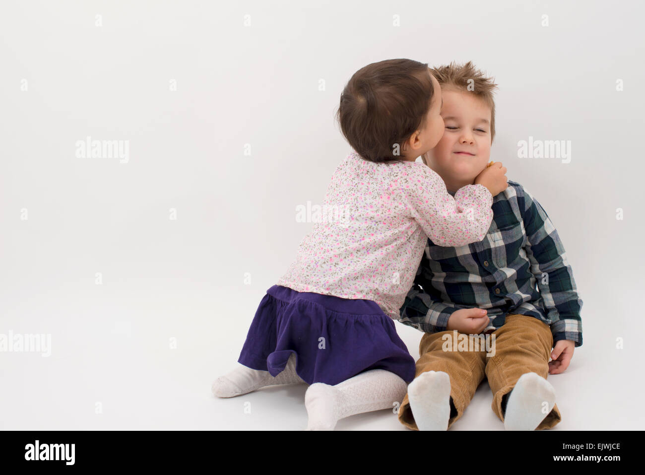 kleines Mädchen küssen ihr älteren Bruder auf die Wange, isoliert Stockfoto