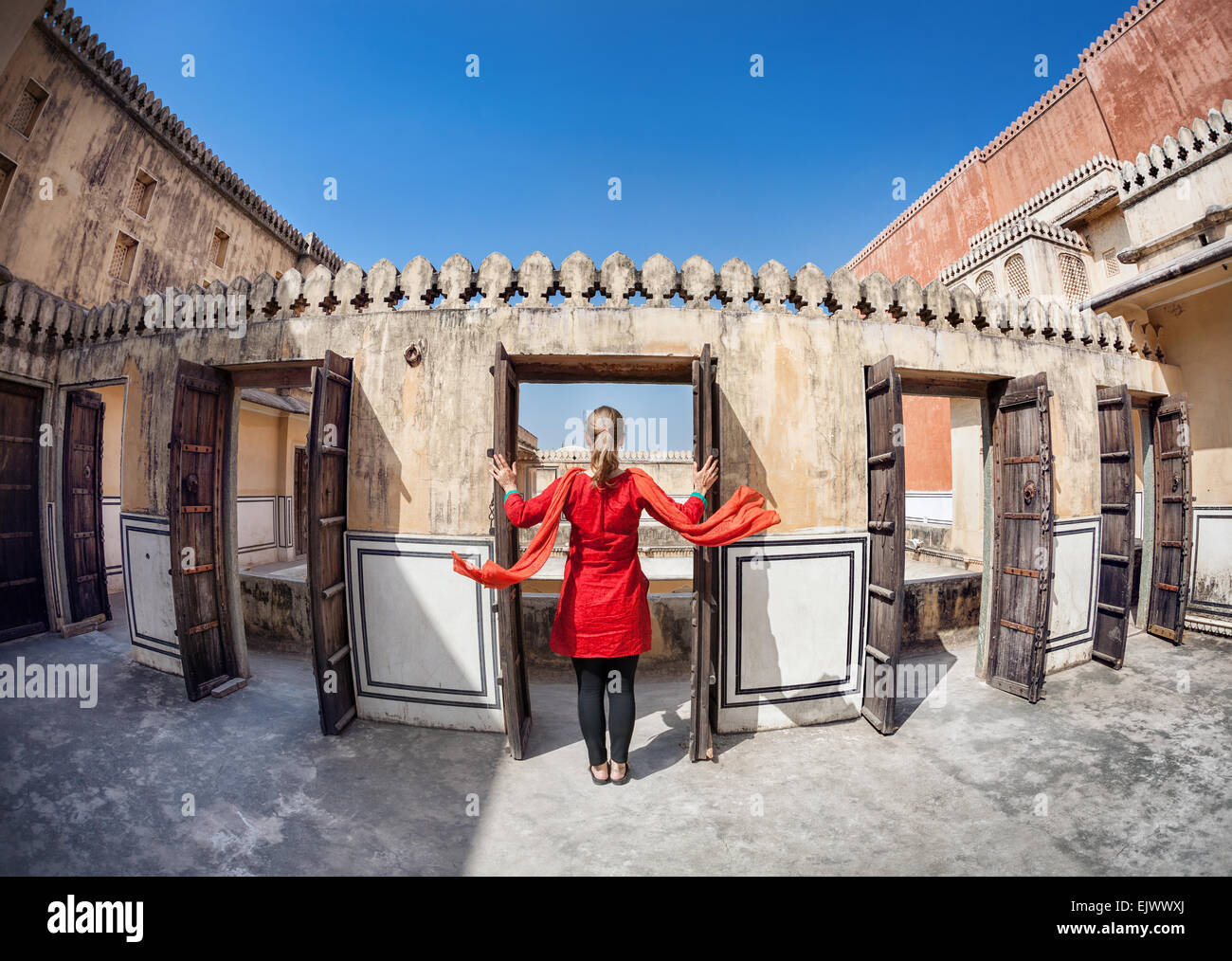 Frau im roten Kleid mit Schal Öffnen der Tür in Hawa Mahal, Rajasthan, Indien Stockfoto
