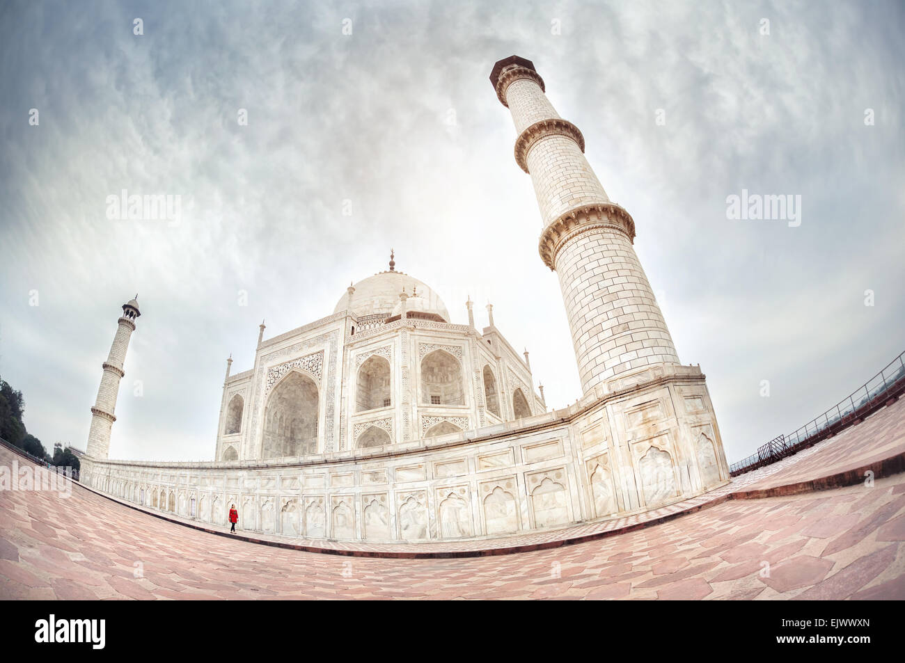 Frau in rot, die zu Fuß in der Nähe von Taj Mahal in dramatischen Himmel in Agra, Uttar Pradesh, Indien Stockfoto