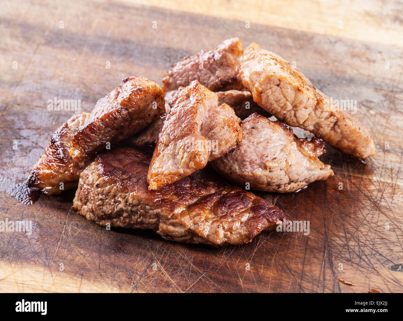 Gebratene Fleischstücke auf Holzbrett. Stockfoto