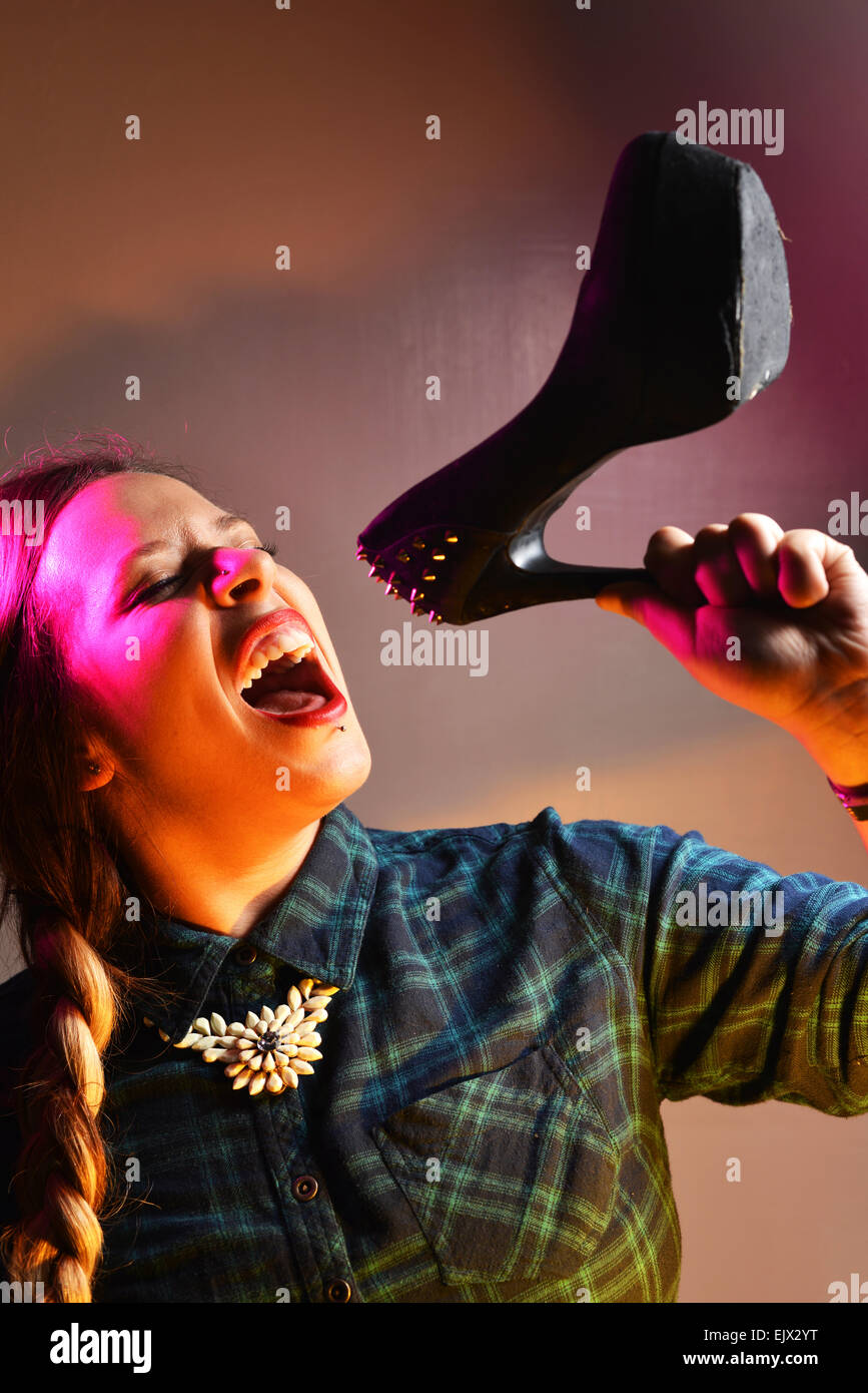 Kerrianne Covell, eine ehemalige X Factor Kandidatin vorgibt, einen Schuh als Mikrofon verwenden. Zuvor arbeitete sie in einem Schuhgeschäft. Stockfoto