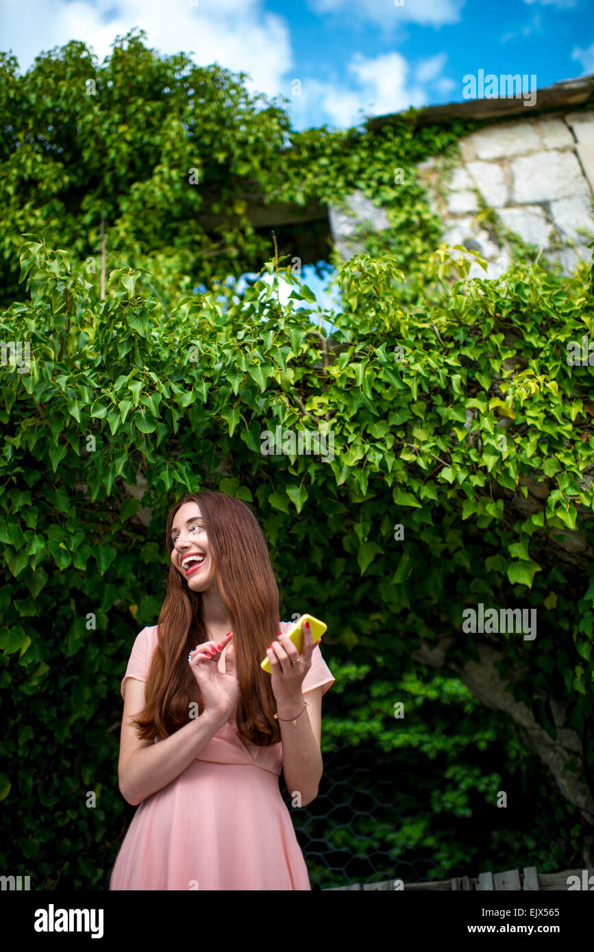 Frau mit Telefon auf grünen Efeu Hintergrund Stockfoto