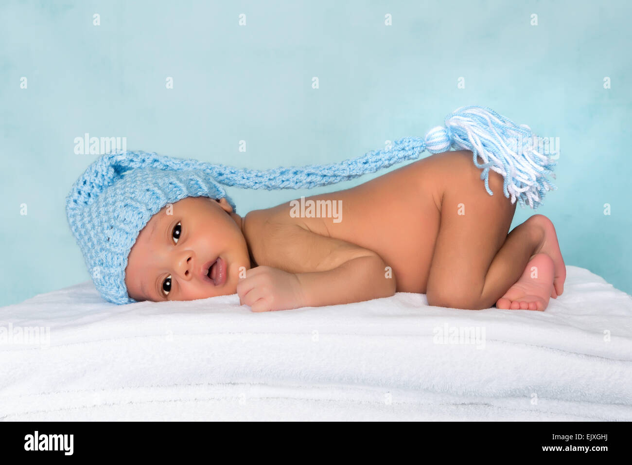 Entzückende schwarze Baby wach mit blauer Strickmütze Stockfoto