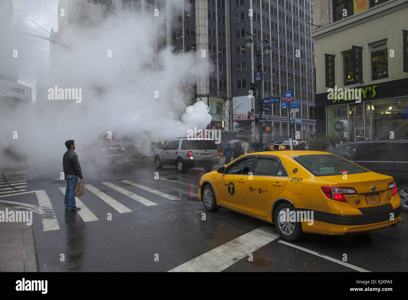 Vom Himmel regnen und Dampf freigesetzt unter der Straße in Midtown Manhattan, Broadway & 32nd Street, NYC. Stockfoto